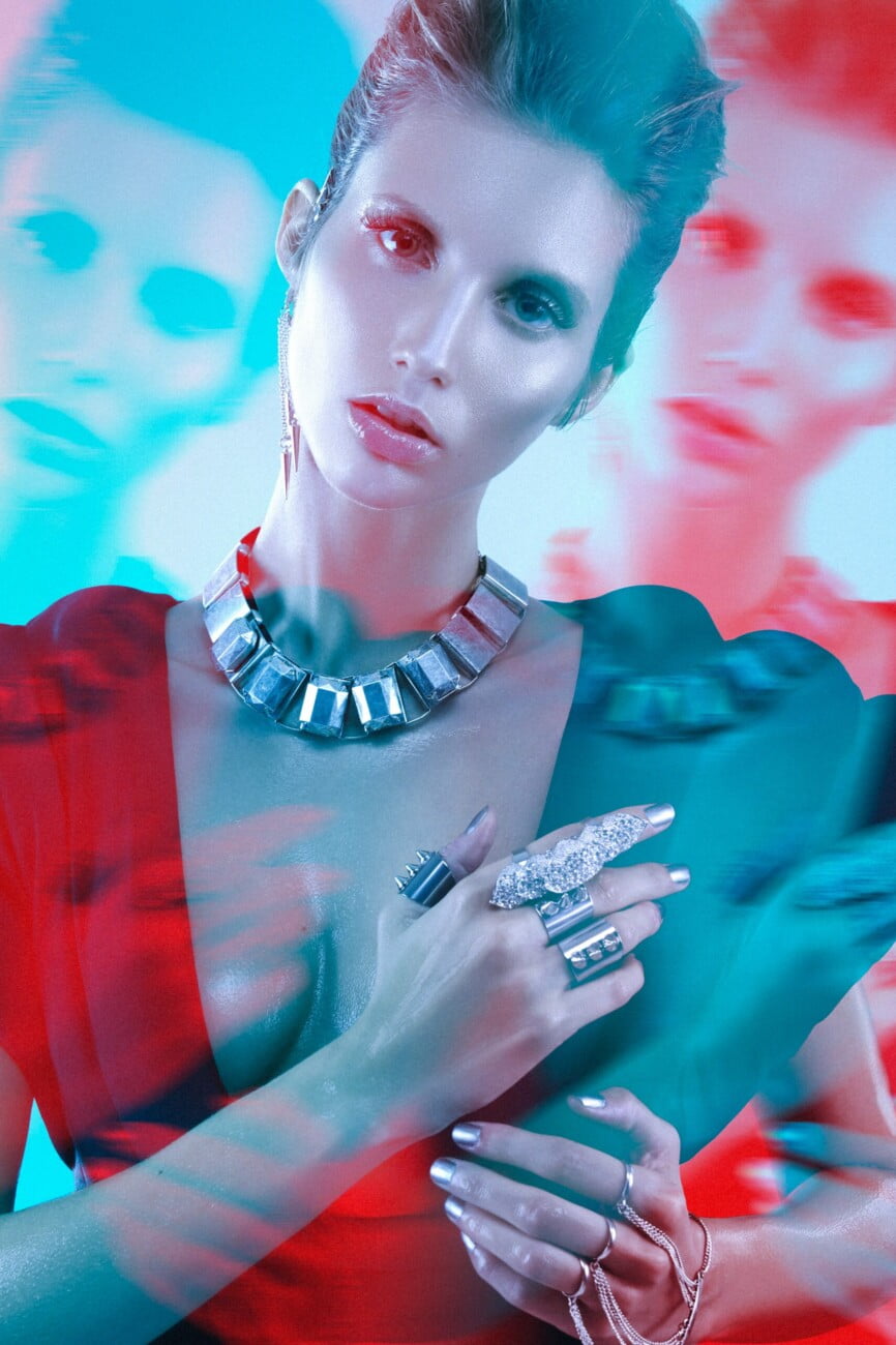 Graphic depiction of model Adeline Petit adorned with exquisite jewelry, showcased in an electric blue and red artistic image by photographer Etienne Delorme for Faust Magazine.