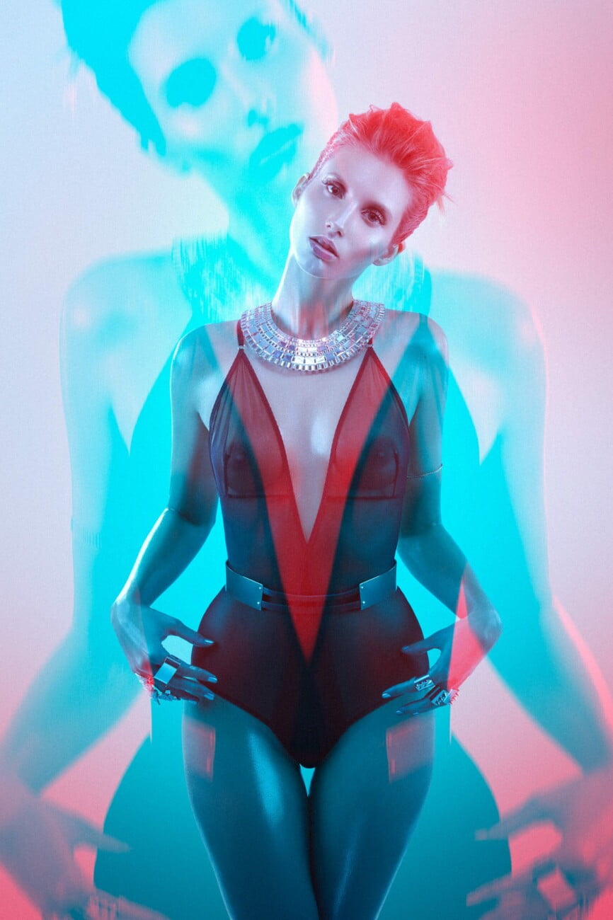 Incredible shining body dressed in a transparent bodysuit revealing her magnificent bare breasts of model Adeline Petit adorned with magnificent jewels, captured in a very graphic electric blue and red artistic image by photographer Etienne Delorme for Faust Magazine.